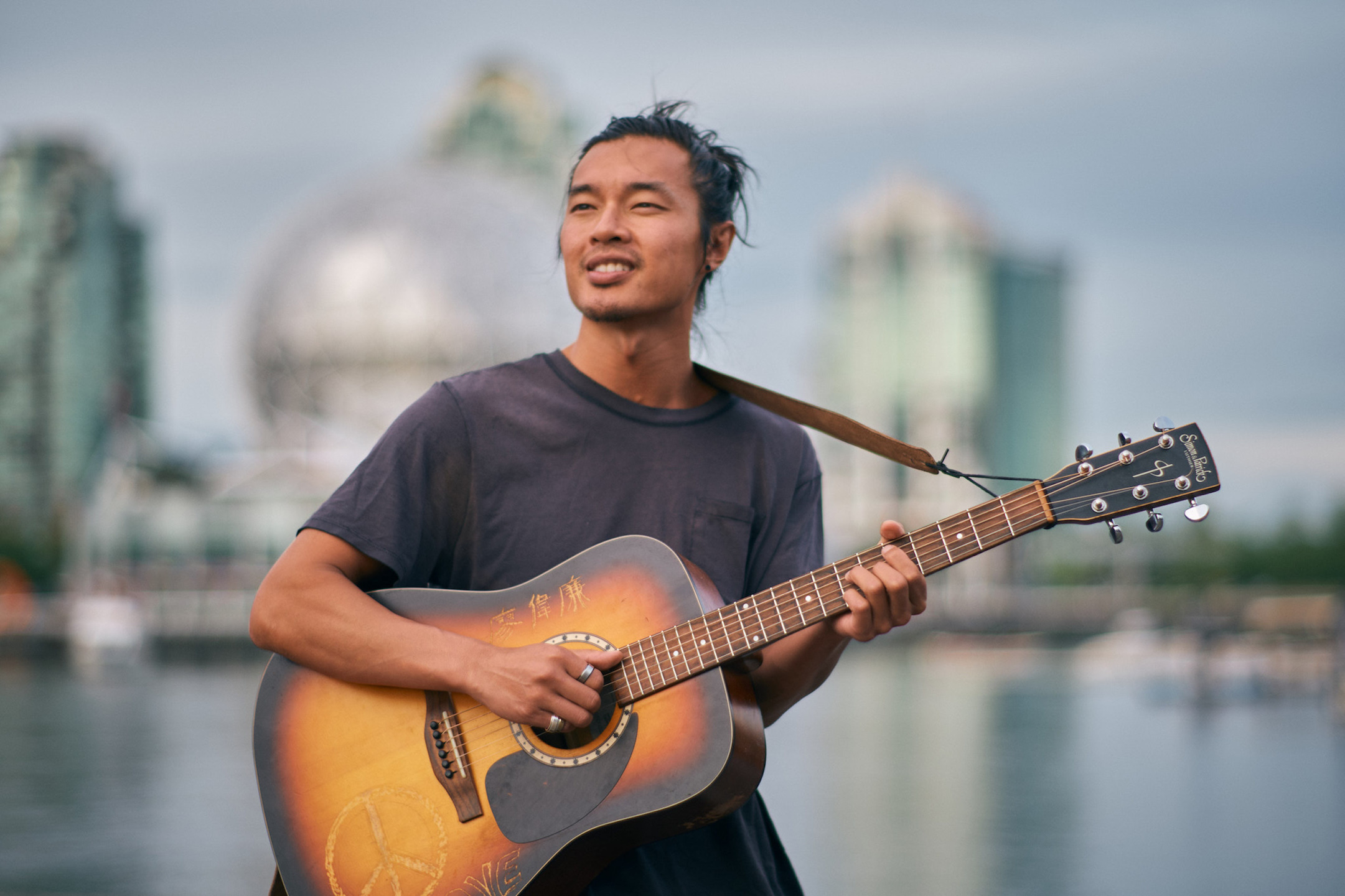 Portrait of Daniel Lew in an outdoor setting with a brown guitar.
