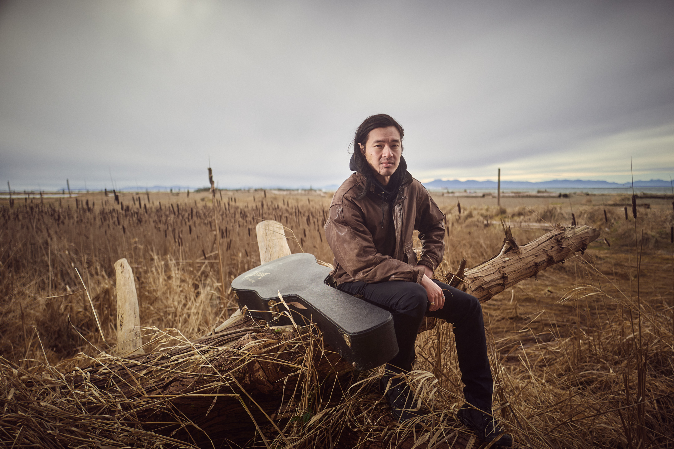 Portrait of Daniel Lew, standing in a field of dry grass.